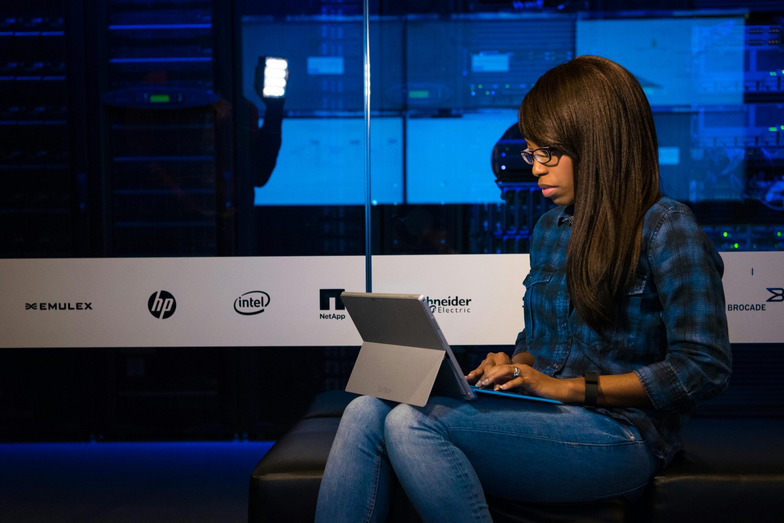 Professional woman working on laptop in a server room, showcasing technology and remote work.